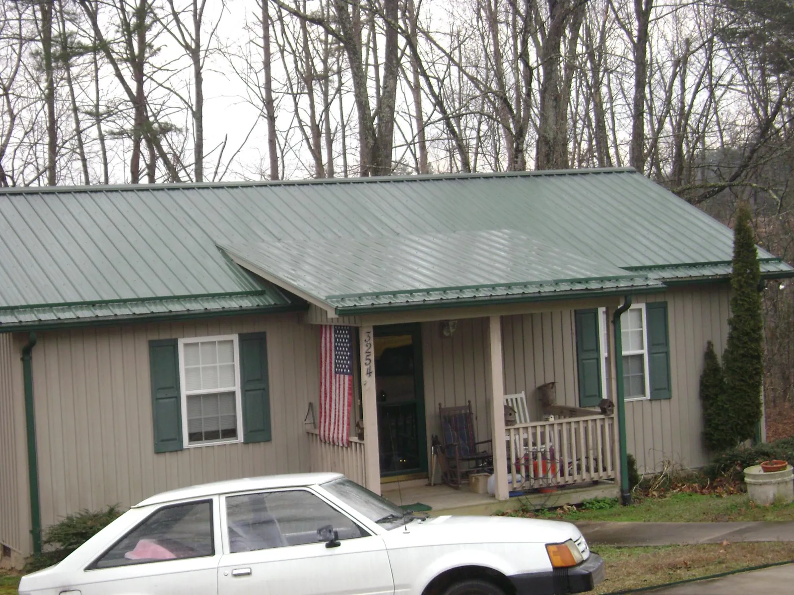 Green metal roof and front porch on a tan sided cottage in Wallace